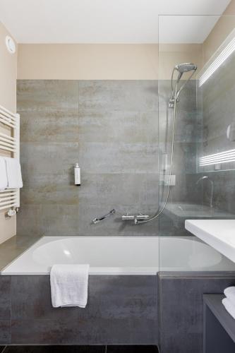 a bathroom with a bath tub and a shower at Enjoy Hotel Blankenberge - Pantheon Palace By WP Hotels in Blankenberge