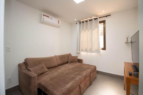 a living room with a brown couch and a window at OZPED Flats Particulares Edifício Life Resort in Brasilia