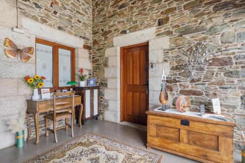 a room with a wooden desk and a stone wall at Adega in Ordes