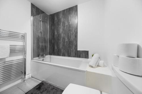 a white bathroom with a tub and a toilet at Budget 2-Bed House 10mins to Leeds City Centre in Leeds