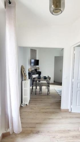 Cette chambre blanche dispose d'une table et d'une salle à manger. dans l'établissement Le Premium, entre Paris & Disney avec Parking Gratuit, à Noisy-le-Grand