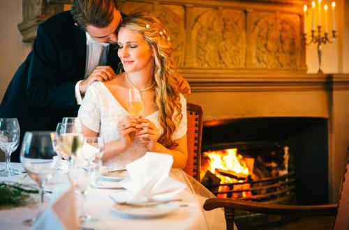 a bride and groom sitting at a table in front of a fireplace at Vienna House Easy by Wyndham Castrop-Rauxel in Castrop-Rauxel