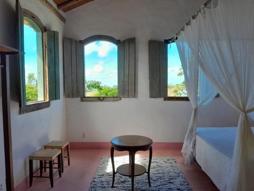 una camera con un letto e un tavolo e due finestre di Casa Trancoso perto quadrado praia a Porto Seguro