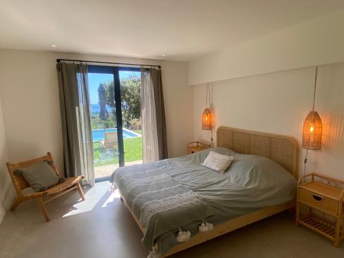 une chambre avec un lit, une fenêtre et une chaise dans l'établissement villa la Chamade, superbe vue mer, 12 pers, piscine, à La Croix-Valmer