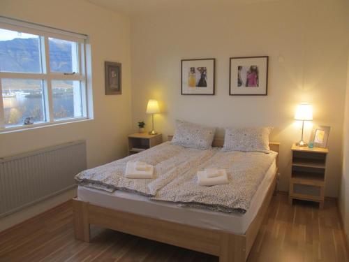 a bedroom with a bed and two lamps and a window at G4 Apartment in Grundarfjordur