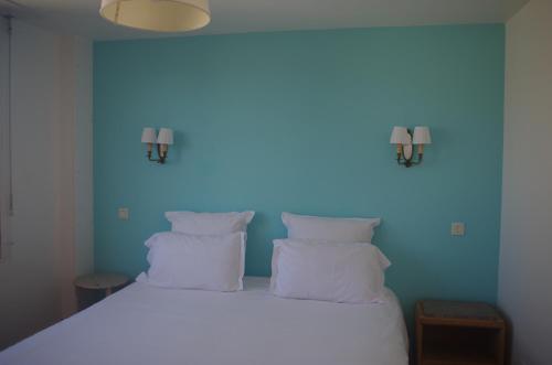 a bedroom with a white bed with a blue wall at Hotel Richelieu in Calais