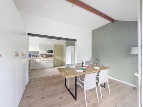 une salle à manger avec une table en bois et des chaises blanches dans l'établissement Evasion Côtière Tranquillité entre Forêt et Océan, à Vielle-Saint-Girons