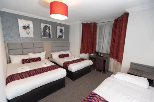 a hotel room with two beds and a television at Euro Hotel in London