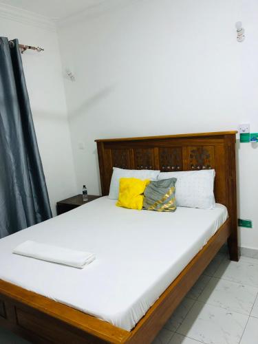 a bed with white sheets and yellow pillows at Queens Luxury Studio Mombasa in Mombasa
