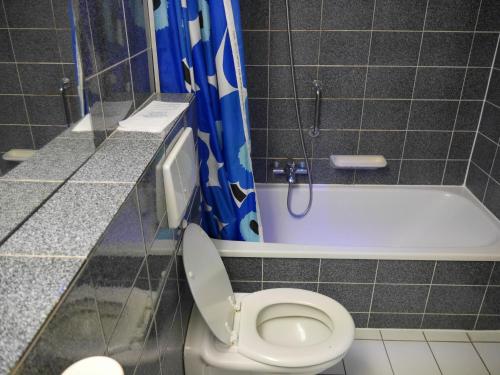 
a bathroom with a toilet, sink, and shower stall at Hotel Maxim in De Panne
