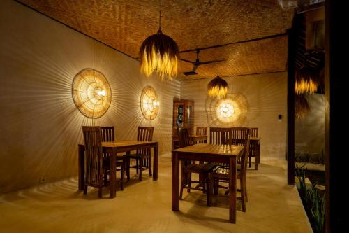 a dining room with wooden tables and chairs and lights at Wellhouse Villas in Nusa Lembongan