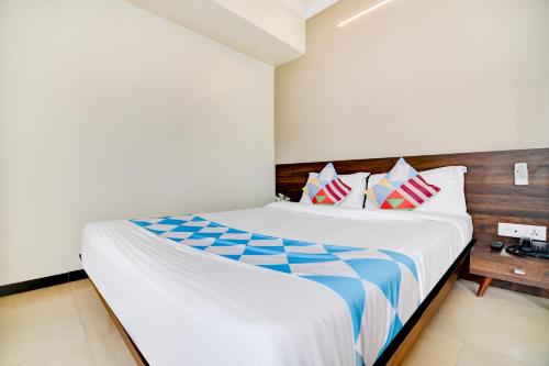 a bedroom with a large white bed with colorful pillows at Hotel O Peaceful Stay Keshav Nagar. in Kharadi