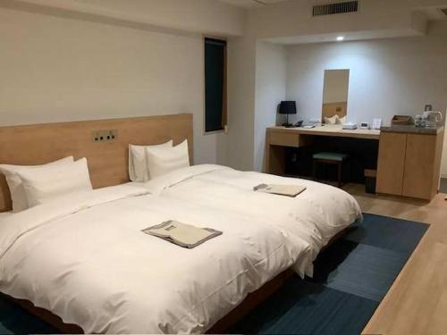 a bedroom with a large white bed and a desk at Awa Kanko Hotel in Tokushima