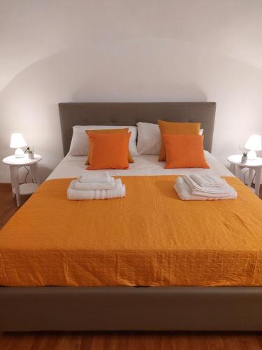 a bed with orange and white pillows and two tables at Maison Partenopea in Naples
