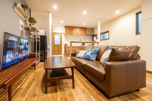 a living room with a brown couch and a table at HOTEL Shibuya Tomigaya in Tokyo