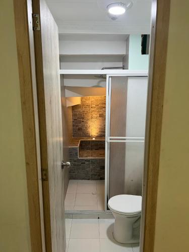 a bathroom with a toilet and a brick wall at APARTAMENTO cerca al UNICO in La Victoria