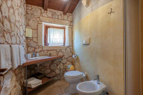 a stone bathroom with a toilet and a sink at Masseria Copertini in Vernole