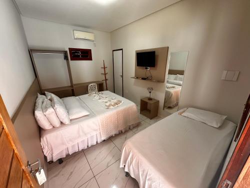 a bedroom with two beds and a tv in it at Pousada Cangaço in Piranhas