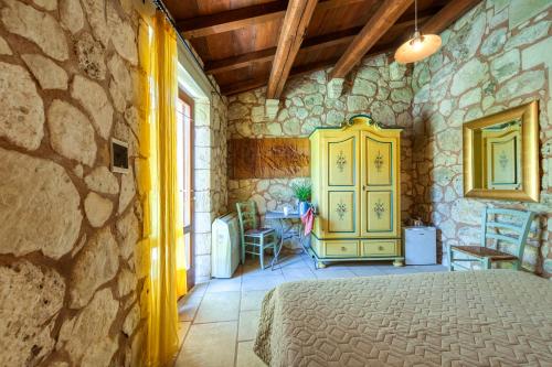 a bedroom with a bed and a stone wall at Masseria Copertini in Vernole