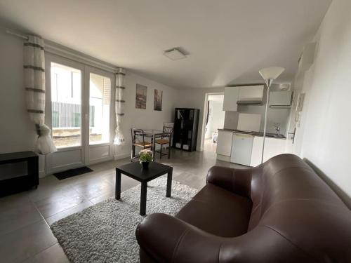 un salon avec un canapé en cuir et une table dans l'établissement T2 avec parking, à La Contrie