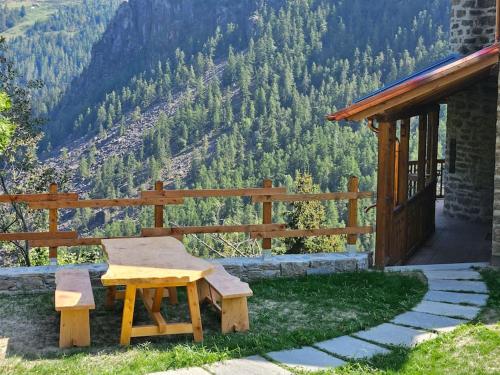 a wooden picnic table on a patio with a view of the mountains at Il Castello nel Bosco, appartamento Torrente in Champorcher