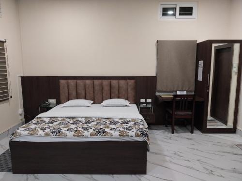 a bedroom with a bed and a desk and a mirror at Bononi in Jorhāt