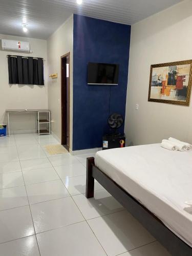 a bedroom with a bed and a blue wall at Temporada BHS Quarto 2 in Barreirinhas