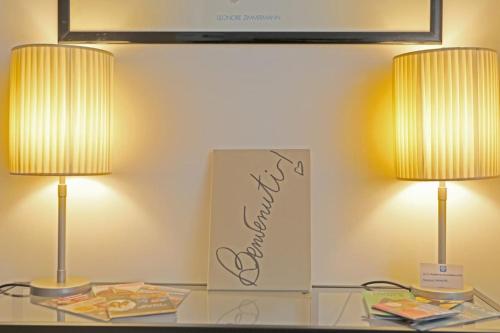 Dos lámparas sobre una mesa de cristal con un cartel. en Appartamento San Donato, en Florencia