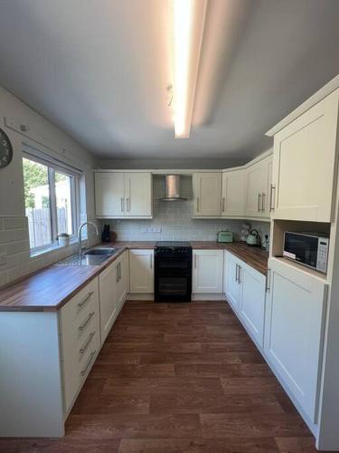 a large kitchen with white cabinets and a sink at Marguerite Retreat in Newcastle