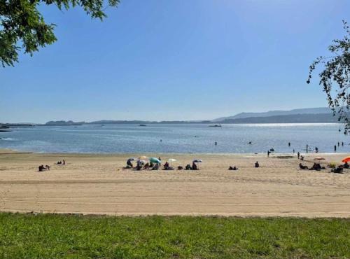 a group of people on a beach with umbrellas at Ático con vistas a la ría de Arosa in Rianjo