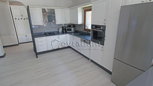 a kitchen with white cabinets and white appliances at Villa Torba Bay by EvTatilim in Torba