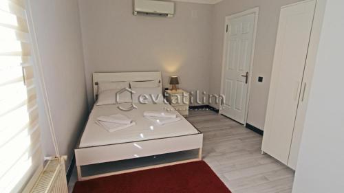 a white bed in a small room with a red rug at Villa Torba Bay by EvTatilim in Torba