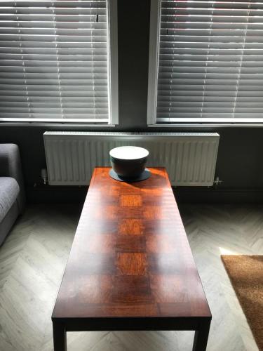 a wooden coffee table in a living room with two windows at Penarth refurbishment in Cardiff