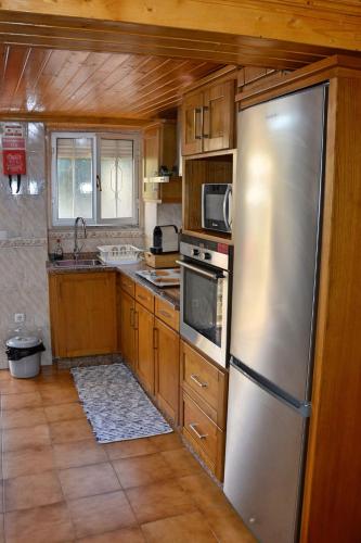 a kitchen with a stainless steel refrigerator and wooden cabinets at Casa da Ti Cristina in Pomares
