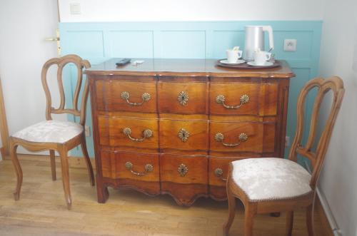 a wooden dresser with two chairs and a dresser with at Hotel Richelieu in Calais