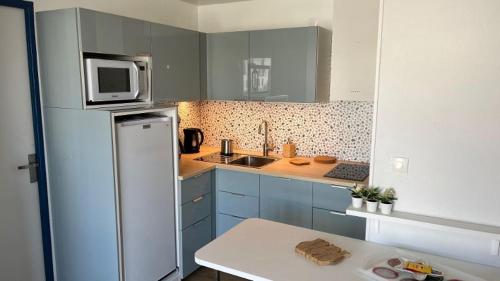 a kitchen with a refrigerator and a microwave at T3 - TERRASSE 30 m2 VUE OCEAN, 2 CHAMBRES, parking privatif et piscine en été in Lacanau-Océan