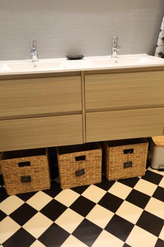 La salle de bains est pourvue d'un lavabo et de paniers sur un sol en damier. dans l'établissement entre ciel et montagne, à Valdeblore