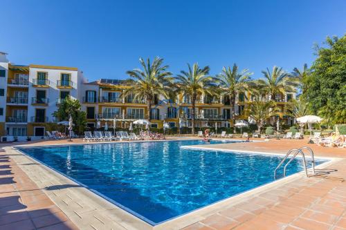 a swimming pool in a resort with palm trees and buildings at Casa das Casinhas by East Algarve Guest in Tavira