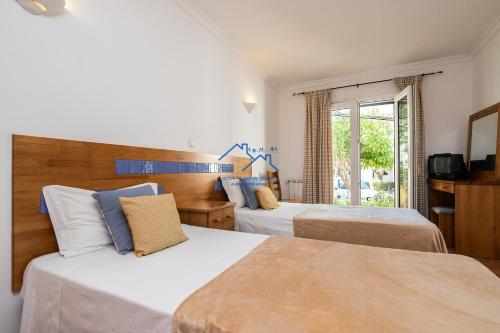 a hotel room with two beds and a window at Casa das Casinhas by East Algarve Guest in Tavira