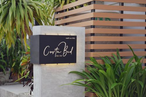 a sign on the side of a building with plants at Costa Bed Hua Hin in Hua Hin