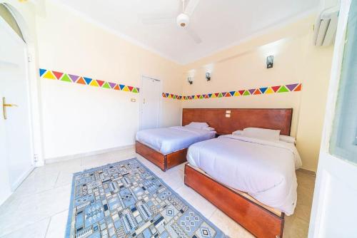 a bedroom with two beds and a rug at Bob Marley Guest House in Aswan