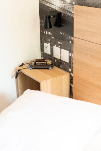 a desk with a phone sitting on top of it at Hôtel Bagatelle Paris Nord Roissy CDG in Goussainville