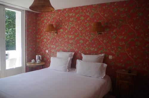 a bedroom with a white bed with red wallpaper at Hotel Richelieu in Calais
