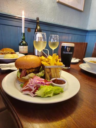 a table with a sandwich and french fries and wine glasses at Foleys Ardmullen Townhouses in Kenmare