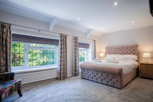 a bedroom with a large bed and two windows at Bryn View – 5 Bedroom Holiday Home – Oxwich in Oxwich