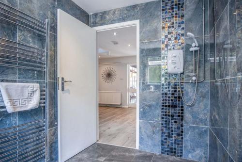 a bathroom with a shower with blue tiles at Bryn View – 5 Bedroom Holiday Home – Oxwich in Oxwich