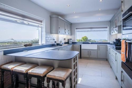 a kitchen with white cabinets and a large island with stools at Channel View – 3 Bedroom House - Rhossili Bay in Oxwich