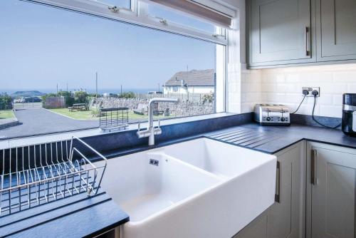 a kitchen with a sink and a large window at Channel View – 3 Bedroom House - Rhossili Bay in Oxwich