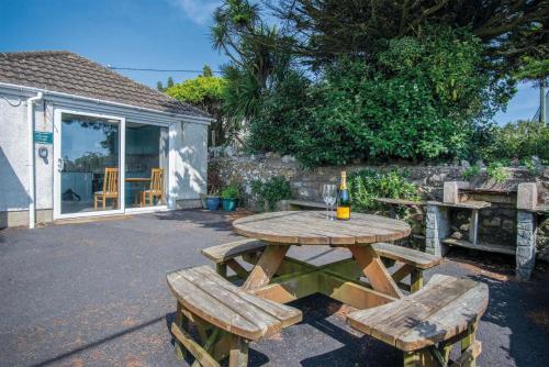 a picnic table with two chairs and a bottle of wine at Lundy Lodge – 1 Bedroom Annex – Rhossili in Rhossili