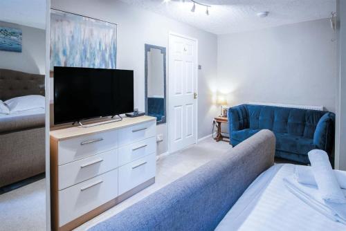 a living room with a tv and a blue couch at Lundy Lodge – 1 Bedroom Annex – Rhossili in Rhossili